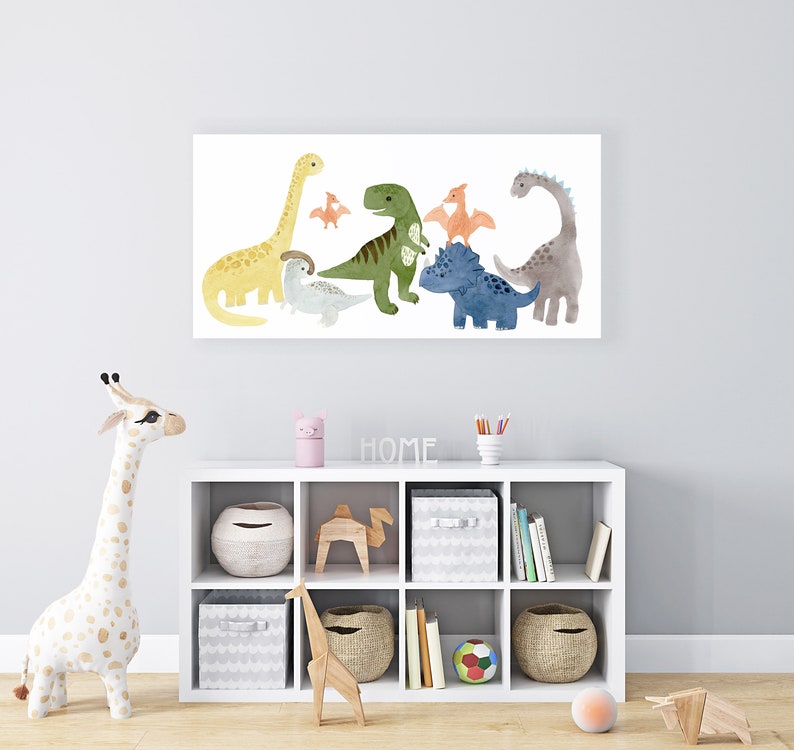 Pode incluir: Uma impress&atilde;o em tela branca com uma ilustra&ccedil;&atilde;o em aquarela de sete dinossauros coloridos. Os dinossauros est&atilde;o dispostos em uma fila, com o maior dinossauro no centro. A impress&atilde;o &eacute; emoldurada com uma borda branca e est&aacute; pendurada em uma parede branca acima de uma prateleira branca com v&aacute;rios itens.