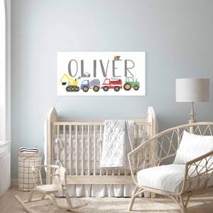 K&ouml;nnte beinhalten: Ein wei&szlig;er Leinwanddruck mit dem Namen "Oliver" in grauer Schrift. Der Name ist mit einer Reihe von bunten Spielzeugfahrzeugen verziert, darunter ein gelber Bagger, ein blauer LKW, ein grauer Betonmischer, ein rotes Feuerwehrauto und ein gr&uuml;ner Traktor.