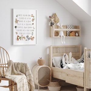 May include: A white framed print with a light brown background and illustrations of woodland animals. The text reads "WISE AS AN OWL, CLEVER AS A FOX, BRAVE AS A BEAR, SILLY AS A SQUIRREL, PLAYFUL AS A BUNNY, CURIOUS AS A RACCOON, KIND AS A DEER".
