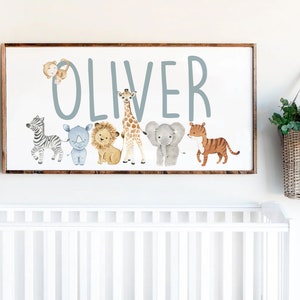 May include: A wooden sign with the name "Oliver" written in blue paint. The sign is decorated with a row of watercolor animal illustrations, including a monkey, zebra, rhinoceros, lion, giraffe, elephant, and tiger.