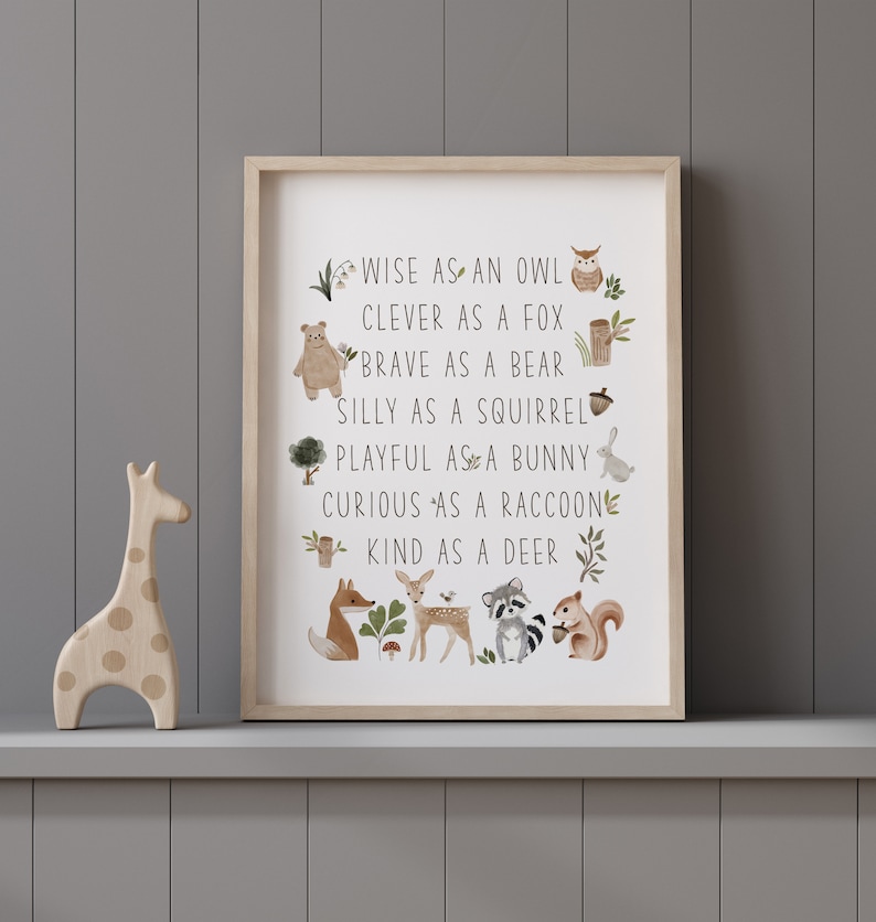 May include: A framed print with a white background and brown text that reads "WISE AS AN OWL, CLEVER AS A FOX, BRAVE AS A BEAR, SILLY AS A SQUIRREL, PLAYFUL AS A BUNNY, CURIOUS AS A RACCOON, KIND AS A DEER". The text is surrounded by illustrations of animals, including an owl, fox, bear, squirrel, bunny, raccoon, and deer.
