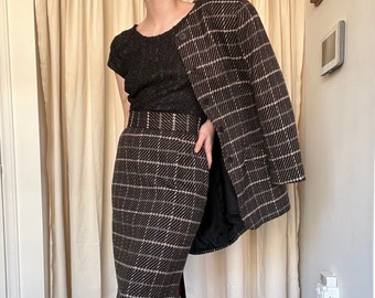 May include: A brown and beige plaid skirt suit with a black top and black boots.