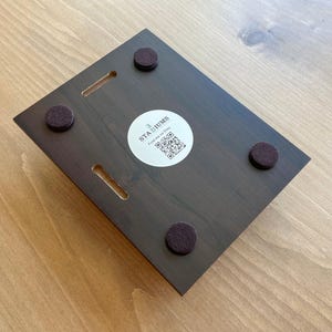 Może przedstawiać: Drewniana tabliczka w ciemnobrązowym kolorze z tekstem "3 Stadiums Find me on Etsy" i kodem QR. Tabliczka ma cztery czarne filcowe podkładki na spodzie.