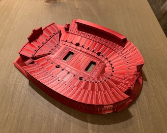May include: A red 3D printed model of Ohio Stadium, home of the Ohio State Buckeyes. The model features the stadium's iconic horseshoe shape and includes the words "Buckeyes" and "Ohio Stadium" on the field.