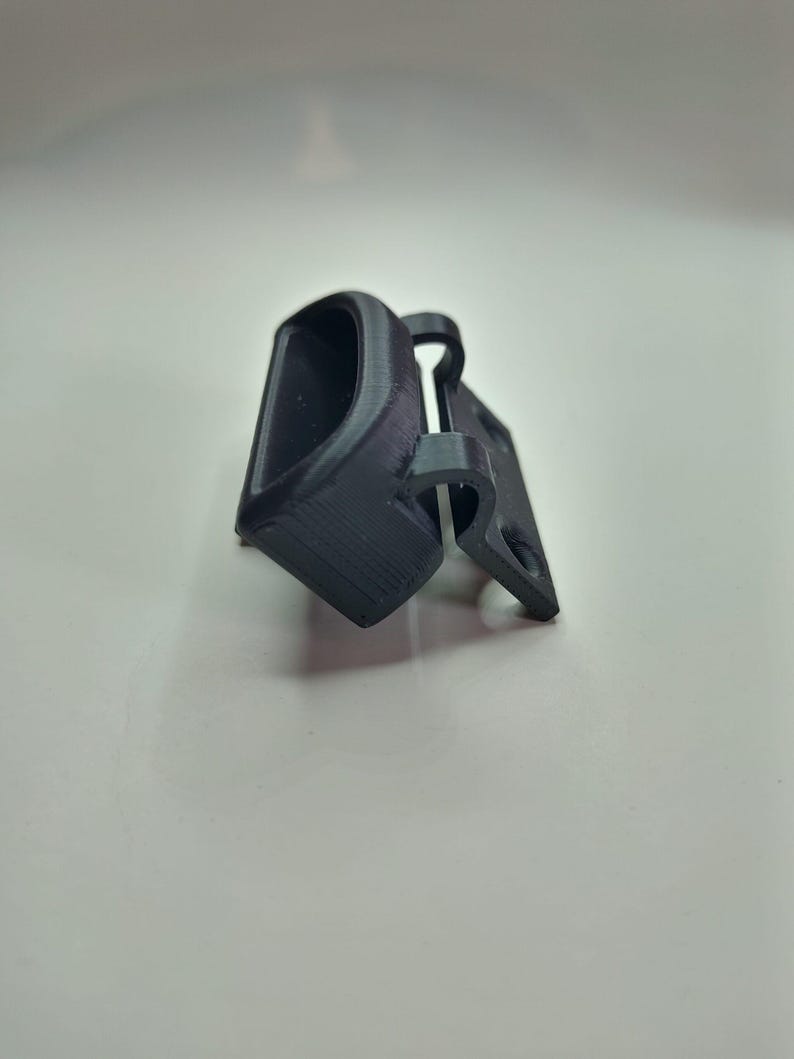 Puede incluir: Una bisagra de pl&aacute;stico negro con una peque&ntilde;a abertura rectangular. La bisagra est&aacute; dise&ntilde;ada para ser utilizada para una puerta o una tapa.