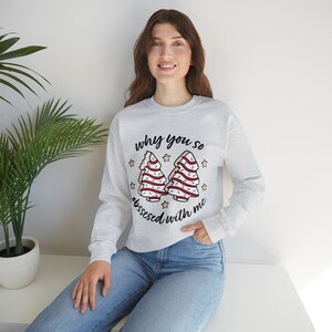 May include: A gray sweatshirt with a Christmas tree design and the text "why you so obsessed with me".