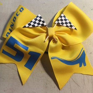 May include: Yellow hair bow with blue dinosaur and number 51, decorated with black and white checkered flags.