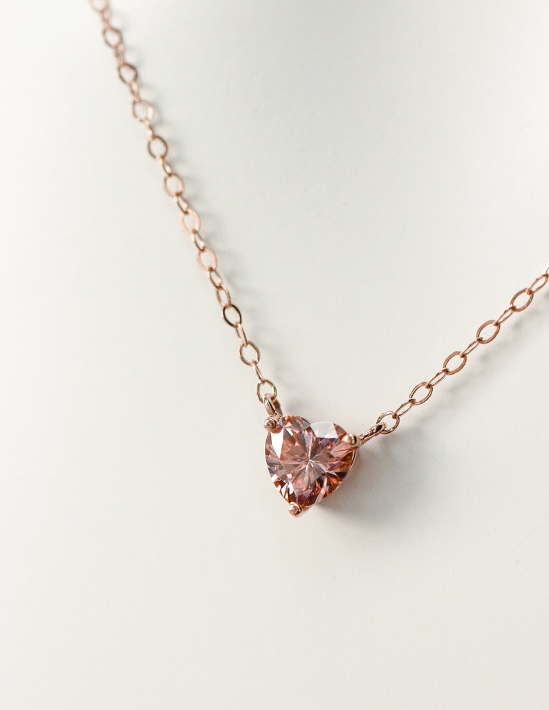 Puede incluir: Un delicado collar de cadena de oro rosa con un colgante de piedra preciosa rosa en forma de coraz&oacute;n.