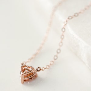 Puede incluir: Un delicado collar de oro rosa con un colgante de coraz&oacute;n en capas.