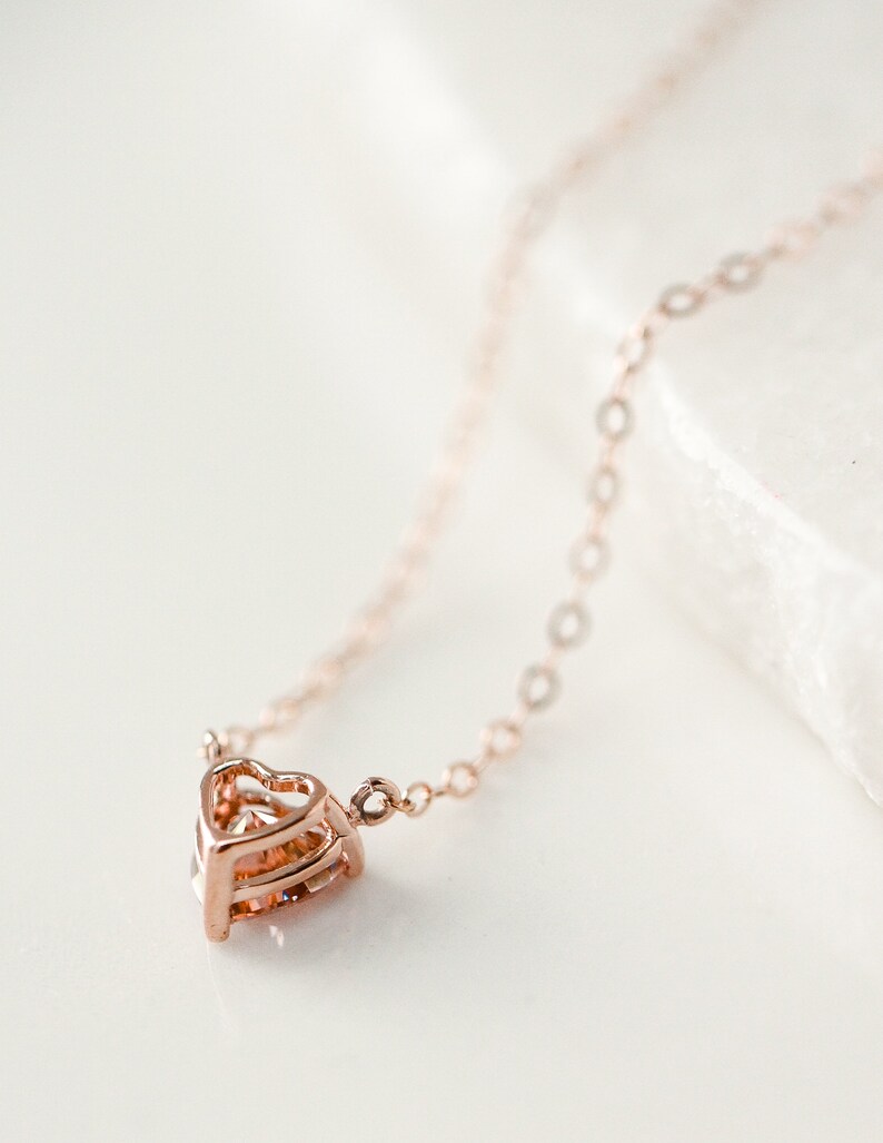 Puede incluir: Un delicado collar de oro rosa con un colgante de coraz&oacute;n en capas.