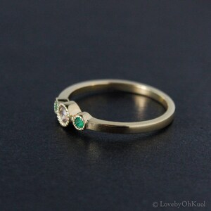 K&ouml;nnte beinhalten: Ein Goldring mit drei Steinen. Der mittlere Stein ist ein runder, klarer Stein, und die beiden Steine an den Seiten sind gr&uuml;n.