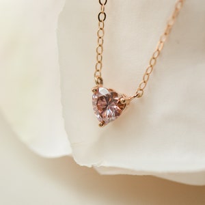 Puede incluir: Un delicado collar de oro rosa con un colgante de piedra preciosa rosa en forma de coraz&oacute;n.