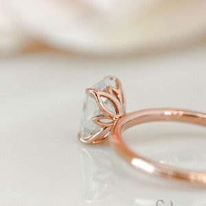 May include: A rose gold engagement ring with a square-shaped diamond set in a delicate floral design.