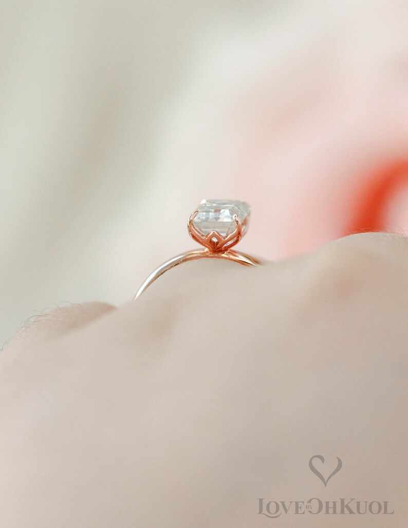 May include: A rose gold engagement ring with a square-shaped diamond.