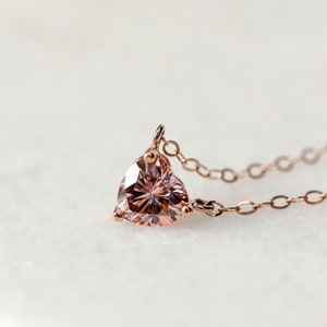 Puede incluir: Un delicado collar de oro rosa con un colgante de piedra rosa en forma de coraz&oacute;n.