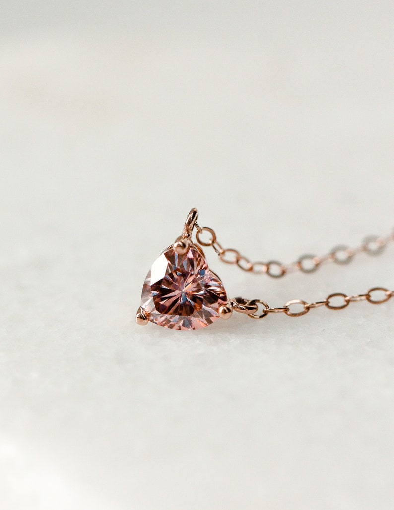 Puede incluir: Un delicado collar de oro rosa con un colgante de piedra rosa en forma de coraz&oacute;n.