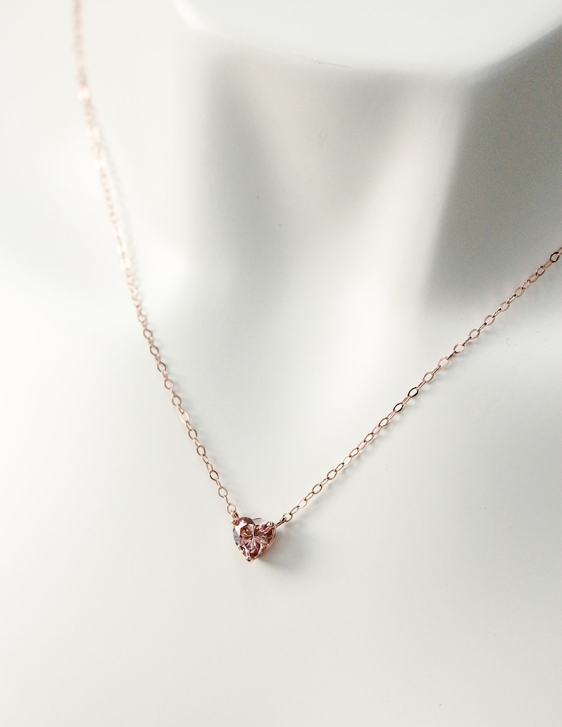 Puede incluir: Un delicado collar de oro rosa con un peque&ntilde;o colgante en forma de coraz&oacute;n rosa.