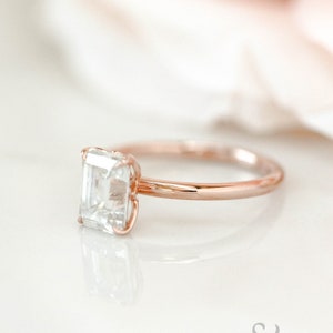 May include: A rose gold engagement ring with a square-shaped diamond.