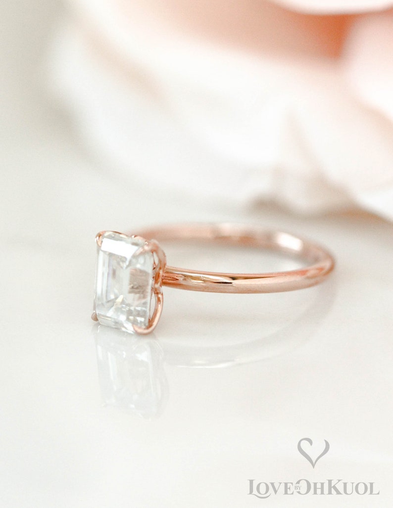 May include: A rose gold engagement ring with a square-shaped diamond.