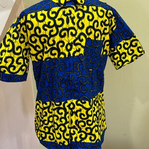 May include: A short-sleeved button-up shirt with a blue and yellow geometric pattern. The pattern features black swirls on a yellow background and blue swirls on a blue background.