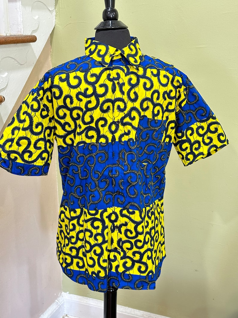 May include: A short-sleeved button-up shirt with a yellow and blue patterned design. The pattern features black swirls on a yellow background and blue swirls on a blue background.