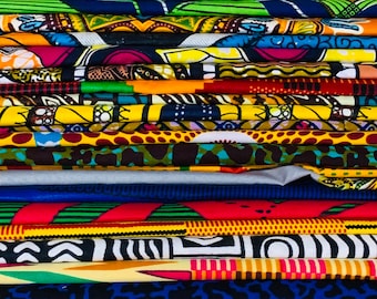 May include: A stack of colorful African wax print fabrics. The textiles feature a variety of bold patterns and vibrant colors, including yellow, green, blue, and red. The fabrics are neatly folded, showcasing the diverse designs.