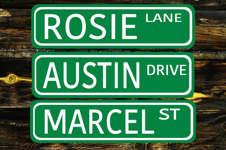May include: Three green street signs with white lettering. The top sign reads "ROSIE LANE", the middle sign reads "AUSTIN DRIVE", and the bottom sign reads "MARCEL ST".