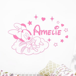 May include: Pink wall decal featuring a sleeping cartoon mouse holding a plush bunny, a cloud, stars, and hearts. The name "Amelie" is written in a cursive font.