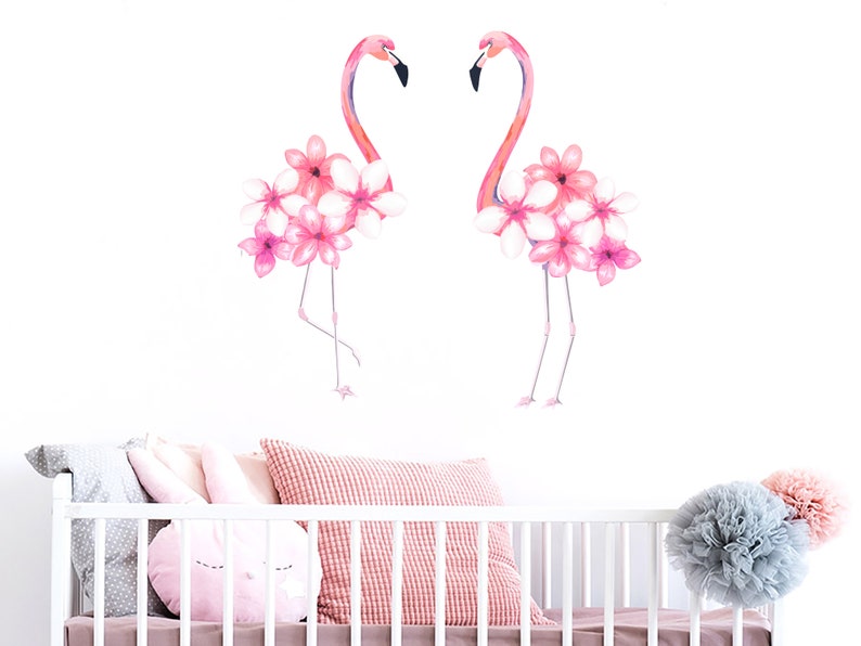 May include: Two pink flamingos with pink flowers on their heads, against a white background. The flamingos are facing each other.