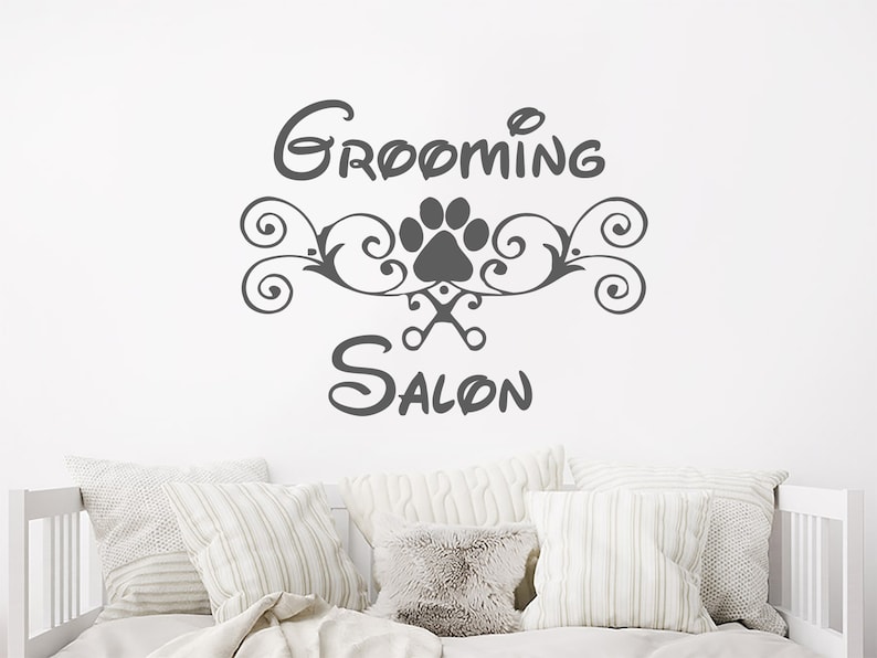 Pode incluir: Um adesivo de vinil cinza com o texto "Grooming Salon" em uma fonte estilizada. Uma pegada com tesouras est&aacute; no centro do design.