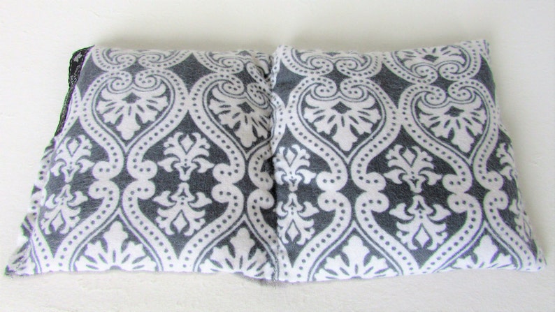 Puede incluir: Dos almohadas rectangulares con un patr&oacute;n de damasco gris y blanco. El patr&oacute;n presenta un dise&ntilde;o floral repetitivo. Las almohadas est&aacute;n hechas de una tela suave y se colocan una al lado de la otra sobre una superficie blanca.