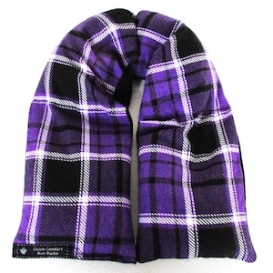 May include: A purple, black, and white plaid rice pack. The pack is rectangular with rounded ends and a central opening. The text "Divine Comfort Rice Packs" is printed on a small black label.