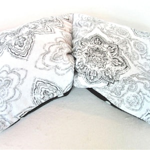 May include: A white and black patterned pillow with a black border. The pillow is made of fabric and has a soft, comfortable feel.