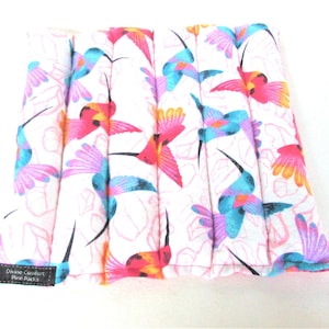 May include: White fabric hot pack with a colorful hummingbird print. The pack is divided into sections and has a black label that reads "Divine Creations Hot Pack".