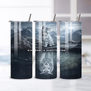 May include: A stainless steel tumbler with a mountain and water scene. The tumbler features a kitten and a tiger reflection, with the text "MINDSET IS EVERYTHING". The tumbler has a silver straw and lid.