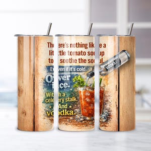 Op de afbeelding: Een roestvrijstalen tumbler met een houten plankontwerp. De tumbler heeft een Bloody Mary cocktail illustratie met de tekst "There's nothing like a little tomato soup to soothe the soul. Even if it's cold. Over ice. With a celery stalk. And vodka."