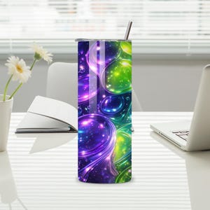 May include: A stainless steel tumbler with a vibrant, abstract design. The tumbler features a pattern of swirling, glowing orbs in shades of purple, blue, and green. It includes a silver lid and a matching straw. The tumbler is on a white desk.
