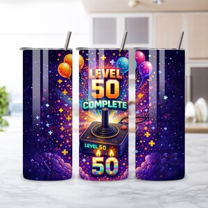 May include: A stainless steel tumbler with a vibrant design for a 50th birthday. The design features a retro video game controller, balloons, confetti, and the text "LEVEL 50 COMPLETE". The tumbler includes a silver straw and a lid.