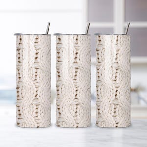 May include: Three stainless steel tumblers with a cream-colored cable knit design. Each tumbler has a silver lid and a silver straw. The tumblers are cylindrical and appear to be insulated.