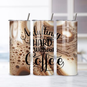 May include: Three stainless steel tumblers with lids and straws, featuring a coffee-like design. The text "Adulting is HARD Without Coffee" is printed on the center tumbler in a black script font. The tumblers are cylindrical and sit on a white surface.