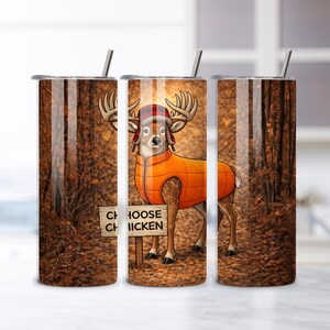 May include: A stainless steel tumbler with a whimsical deer design. The deer wears an orange vest and a hat, standing in a forest scene. The tumbler has a straw and the text "CHOOSE CHICKEN" on a sign.