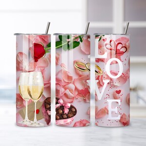 Può includere: Tre bicchieri in acciaio inossidabile con cannucce, con disegni romantici. Uno ha una rosa e calici, un altro anelli e cioccolatini, e l'ultimo dice "LOVE" con cuori e petali.