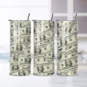 May include: Three stainless steel tumblers with a wrap-around design of hundred-dollar bills. Each tumbler has a silver lid and a silver straw. The tumblers are cylindrical and sit on a white surface.