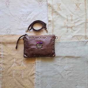 Pochette en cuir vieilli, avec décoration ethnique, clous et pompons