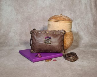 Pochette en cuir vieilli ornée de motifs ethniques, de clous et de pompons.