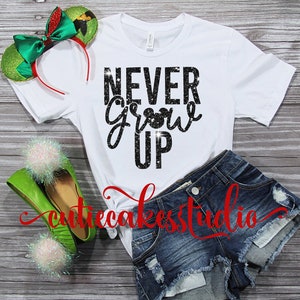 Puede incluir: Camiseta blanca con texto en purpurina negra que dice "NEVER Grow UP" con una pequeña cabeza de Mickey Mouse en la palabra "Grow".