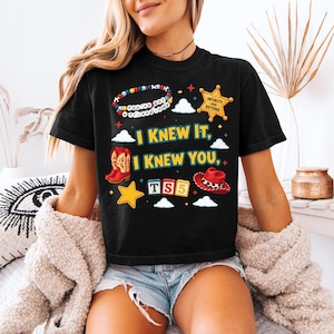 Może przedstawiać: Czarny t-shirt z kr&oacute;tkim rękawem z nadrukiem graficznym zawierającym tekst "I KNEW IT, I KNEW YOU," "YOU'VE GOT A FRIEND IN ME," "INFINITY AND BEYOND," oraz "TS5." Wz&oacute;r przedstawia bransoletkę z koralik&oacute;w, gwiazdę szeryfa, kowbojki, kapelusz i gwiazdki.
