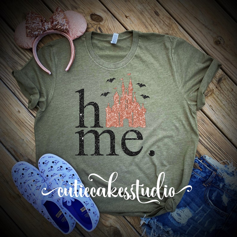 May include: A green t-shirt with the text "home" and a glittery pink castle graphic. The castle is surrounded by bats. The text "cutiecakesstudio" is written in cursive at the bottom of the shirt.