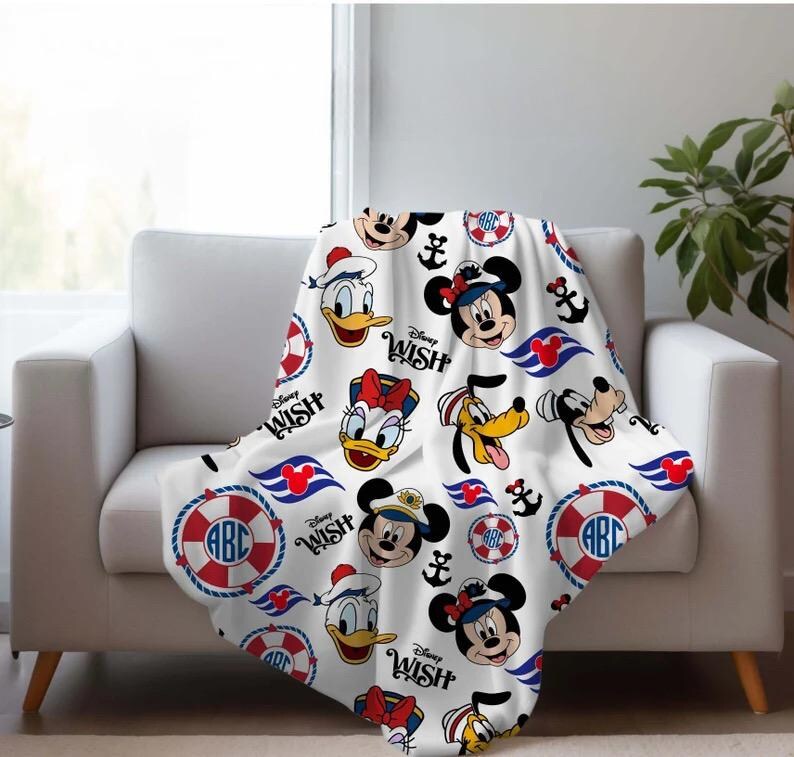 May include: White Disney-themed blanket featuring Mickey Mouse, Minnie Mouse, Donald Duck, Daisy Duck, and Goofy. The blanket has a repeating pattern of Disney characters, anchors, and life preservers with the text "Disney Wish".