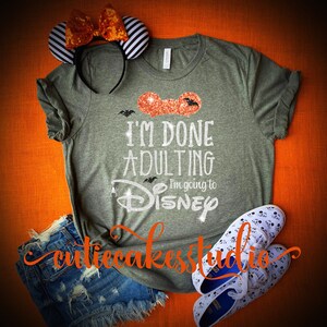 May include: A green t-shirt with a glittery orange Mickey Mouse ear design and the text "I'm done adulting I'm going to Disney".